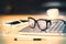 Eyeglasses on laptop keyboard with headphones and diary on wooden table at evening, close up