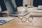 eyeglasses, laptop and smartphone on wooden table in office