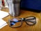 Eyeglasses place on old wooden desk with aluminium cup background