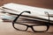 Eyeglasses and stack of newspapers on wooden desk for themes of ophthalmology, poor vision and reading