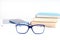 Eyeglasses at the white table with books and tablet on the background. Focus on glasses