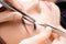 Eyelash extension procedure. Master tweezers sets fake lashes on beautiful woman