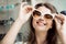 Eyes deserve best lenses and glasses. Portrait of good-looking woman in optician store picking new pair of stylish