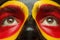 Eyes of German or Belgian sports fan patriot. Painted country flag on man face.