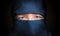 Eyes of young woman veiled with blue niqab scarf. Low key photo