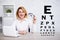 Eyevision test chart and mature business woman using laptop and holding eyeglasses in modern office