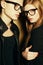 Eyewear concept. Family portrait of gorgeous blond fashion twins in black clothes wearing trendy glasses and posing over golden