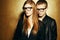 Eyewear concept. Portrait of gorgeous red-haired fashion twins in black clothes wearing trendy glasses and posing over golden