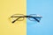 Eyewear placed on a pastel yellow and blue background divides the halves