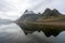 Eystrahorn mountain peaks are reflecting in the calm water on the south coast of Iceland.