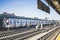 F subway train approaching elevated station in Brooklyn, New York. Train tracks on the outdoor platform