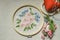 Fabric with embroidered bouquet of wildflowers covered with wooden hoops, colored threads, scissors and a red pillow for needles