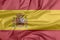 Fabric flag of Spain. Crease of Spanish flag background, a horizontal of red yellow and red; charged with the Spanish coat of arms