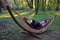 Fabric hammock net in designer hanging shape half moon crescent in park at sunrise springtime green leaves forest and red seduces