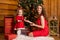 Fabulous Christmas holidays mom and daughter in red dresses decorate the Christmas tree. Cozy family holiday