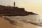 Fabulous landscape view of the beautiful beach with umbrellas and beach beds, Light house on the top of the hill