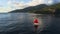 Fabulous scarlet red sail boat floating on quiet ocean water near sea shore with green hills and mountains in summer