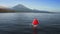 Fabulous scarlet red sail white Jukung boat floating on quiet ocean water near sea shore with huge volcano in summer