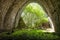 Fabulous stone tunnel with greenery, trees and moss, beautifully lit sun rays