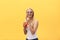 Fabulous woman in sunglasses wearing white t-shirt while holding glass of juice isolated over yellow background