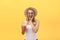 Fabulous woman in sunglasses wearing white t-shirt while holding glass of juice over yellow background