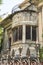 Facade of an abandoned old house with ruined windows and a terrace behind a rusty patterned fence