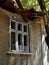 Facade of an abandoned one-story house with broken windows and fallen roof, summer day