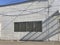 Facade of abandoned white washed building from outside with shadows and blue sky on a sunny day with copy space