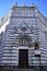 Facade of the baptistery of San Giovanni in Corte framed by the blue sky veiled by light clouds, in piazza del duomo in Pistoia.