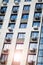 Facade of building with air conditioners. Sunlight reflected in window, vertical view