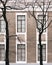 The facade of the building with high Windows. Trees without leaves