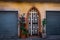 Facade of a building with potted plants on the side of doors with metal safety shutters