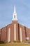 Facade of church with brick wall and white steeple