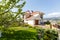 The facade of a classic Mediterranean two-storey cottage in the spring. In front of the cottage there is a green lawn