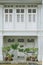 Facade of a conserved Straits Chinese residential terrace house, with white louvered windows and 5-foot passage way