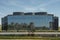 facade of a dark shiny looking steel and glass covered office building and many gardens