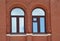 Facade element of a red brick building with two arched windows. Restoration of houses. Architecture