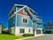 Facade of family house with green lawn in front and blue sky background