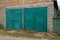 Facade of a gray brick garage with two iron green gates