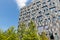 Facade with grey rectangles office building with trees in front