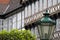 Facade of a half-timbered house in an old town, with a deliberately blurred lantern and a blurred crown of trees in the foreground