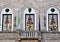 Facade of a historic and important building with two windows, a balcony with French doors, two flags and three coats of arms in Lu