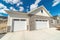 Facade of home with gable roof white garage doors and stone wall against sky