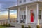 Facade of home with red door porch stairs and yard