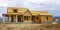 Facade of home under construction against snowy mountain and cloudy sky