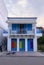 Facade of a house in the Cycladic blue and white style with curtains in the colors of the LGBT flag in the resort town in Greece