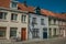 Facade of houses and bicycle with blue sunny sky in an empty street of Bruges.