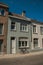 Facade of houses with bicycle and a blue sunny sky in an empty street of Bruges.