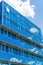 Facade of a modern building. Glass Windows reflected the sky and clouds. Blue gamma