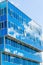 Facade of a modern building. Glass Windows reflected the sky and clouds. Blue gamma